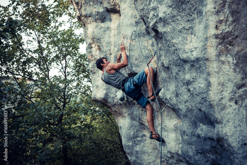 Men climbs an overhanging rock, bouldering