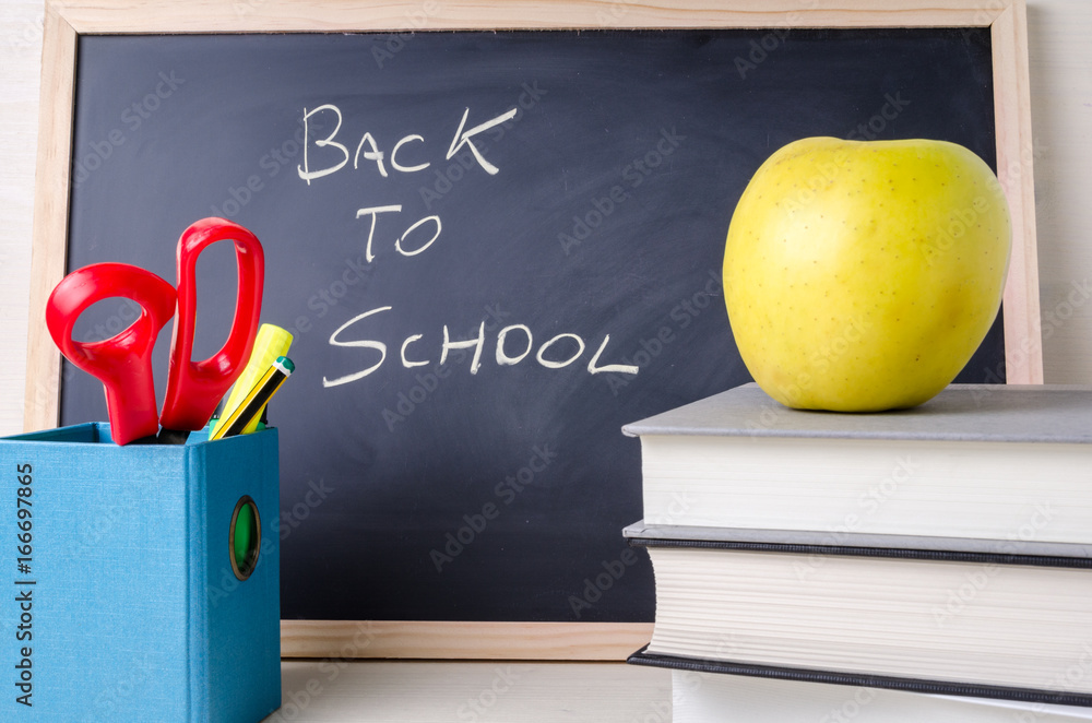 Stationery, Books, Apple and a Blackboard on a Wooden Table. Back to School Concept. Stationery, Books, Apple and a Blackboard on a Wooden Table. Back to School Concept.