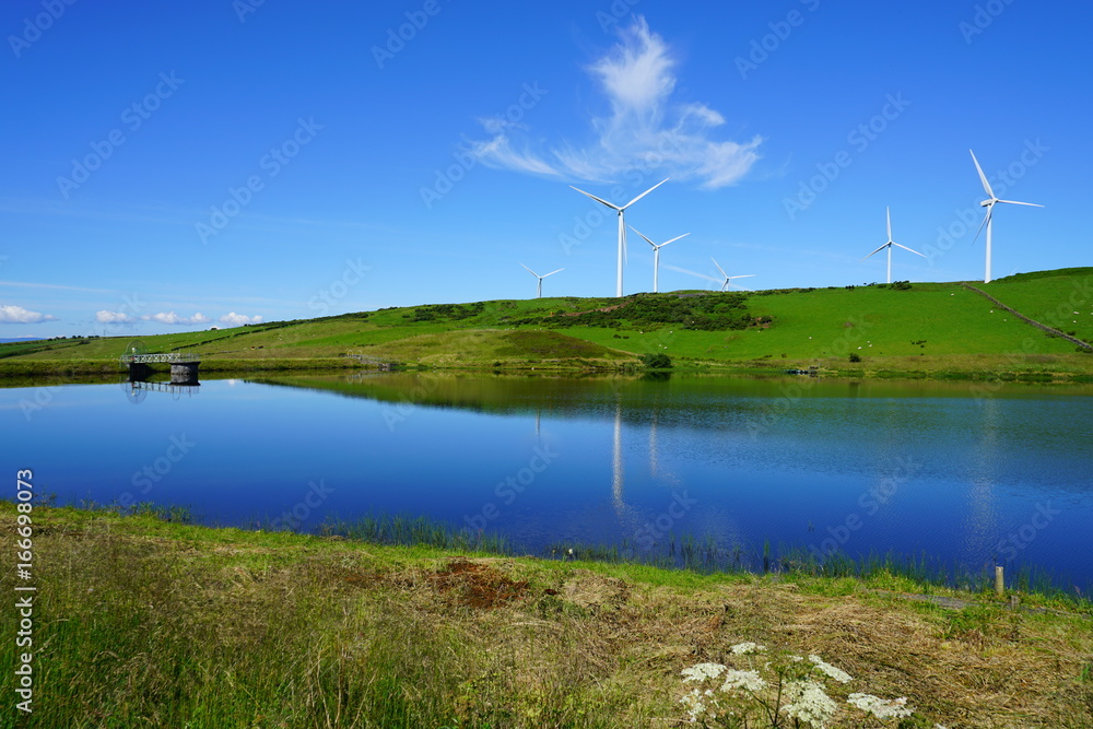 Landscape view of giant wind turbines on a hill overlooking a river in Scotland