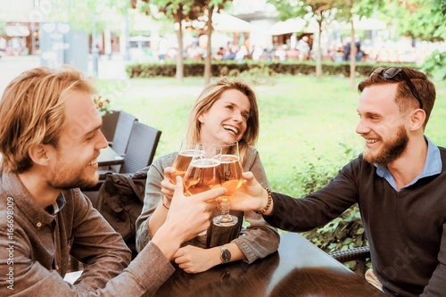 Photography Group of smiling young friends clanging glasses of beer