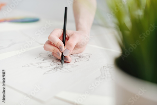 Young female illustrator working on sketches at home office