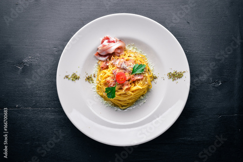 Pasta with bacon in creamy sauce. Italian traditional food. On a wooden background. Top view. Free space for your text.