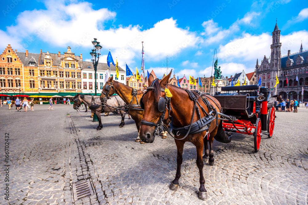 Fototapeta premium Bryczki konne na placu Grote Markt w średniowiecznym mieście Brugge rano, Belgia.