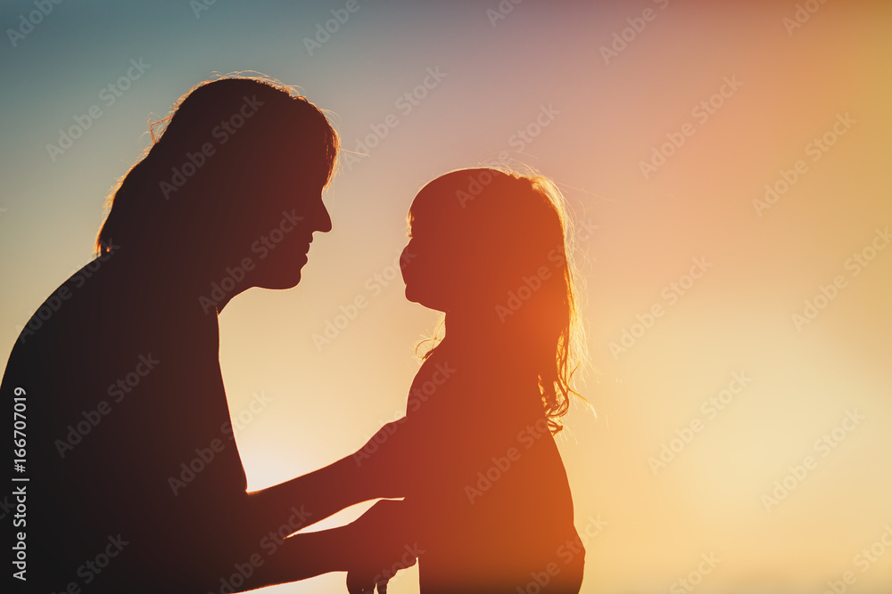 happy mother and little daughter at sunset