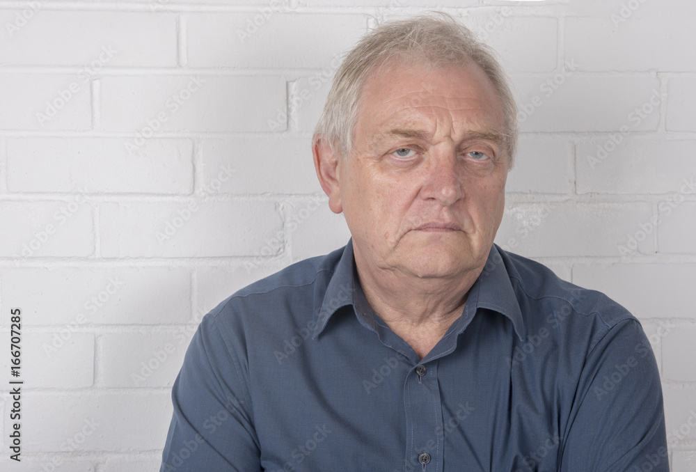 Annoyed mature man with a white brick background and copy space Annoyed mature man with a white brick background and copy space