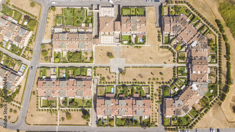 Vista aerea ortogonale di un quartiere periferico della città di Roma. Le costruzioni sono ville moderne e anche l'urbanistica è futuristica. Tanti sono gli alberi piantati intorno alle abitazioni.