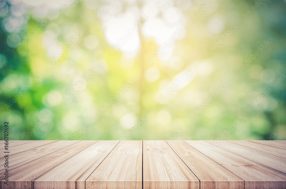 Empty wooden table top with blurred green natural abstract background.