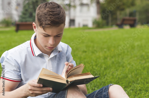 Young man reading a book sitting on the grass