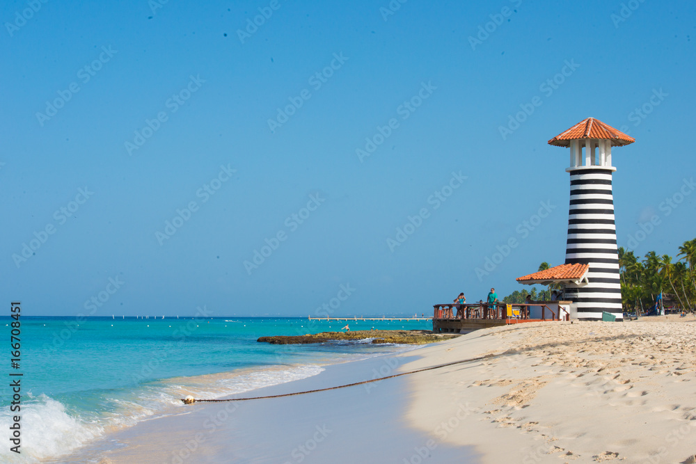 Obraz premium Striped red white lighthouse on the coast of the Caribbean Sea. Dominican Republic.