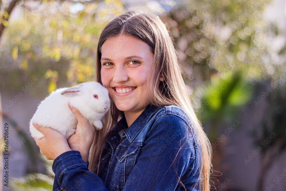 Young teen girl holding a white baby rabbit outdoors Young teen girl holding a white baby rabbit outdoors