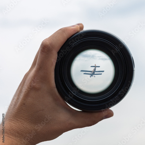 View through spyglass lens to the small airplane in the sky
