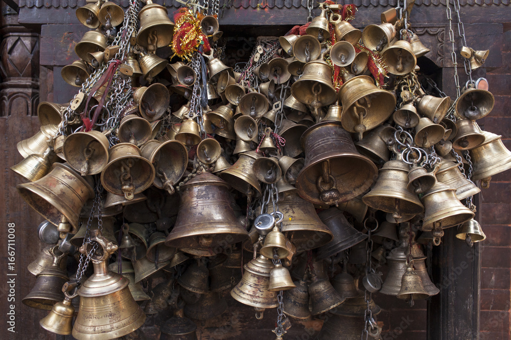 A large bundle of bells stacked together on a temple wall.