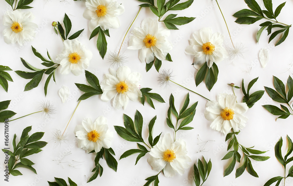 Obraz premium Flat lay floral pattern made of white peony flowers, green leaves and pasque-flower seeds on white background. Top view.