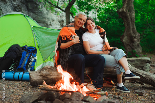 Tent camping couple romantic sitting by bonfire night countryside