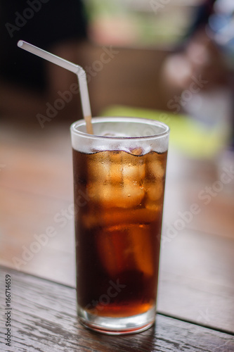 Soft drink with ice in the glass on a table.