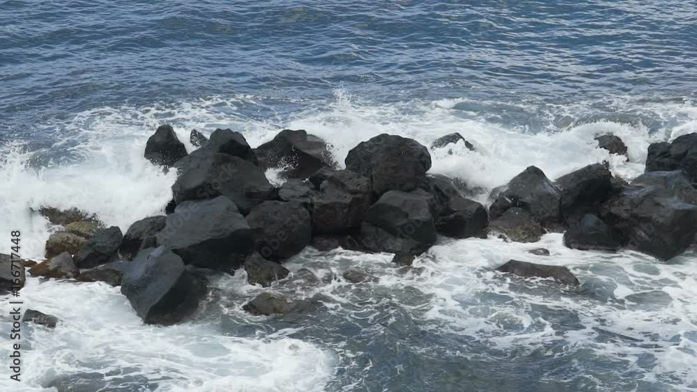 Sea waves hitting against big rocks and breaking into foam, water slow motion Sea waves hitting against big rocks and breaking into foam, water slow motion