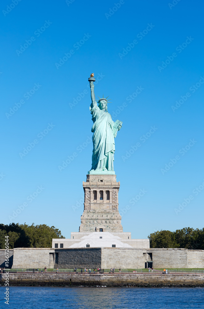 Statue of Liberty with pedestal and Liberty Island in a sunny day, blue sky in New York