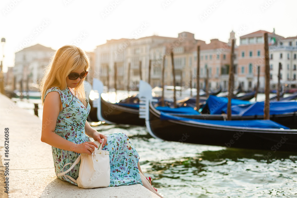 girl sitting on a pier near the canal at the venice. Italy