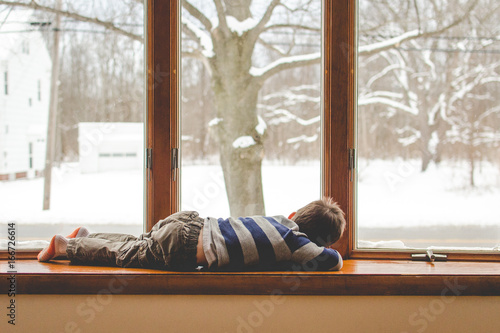 Boy lying beside a snowy window photo