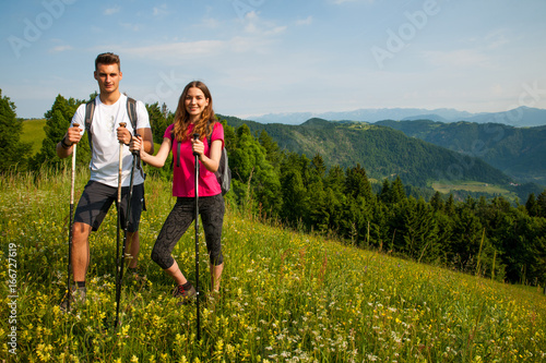 active Beautiful young couple hiking ina nature climbing hill or mountain - man and woman trekking