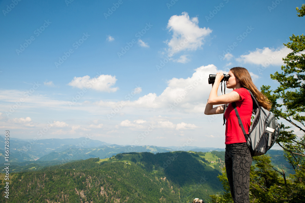 active Young woman looking a mountain landscape with Binoculars