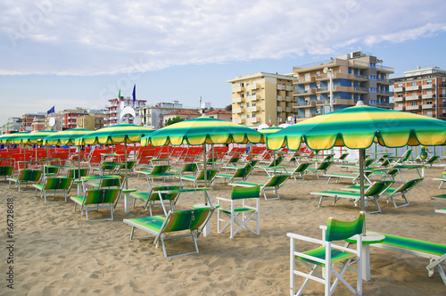 Green umbrellas and chaise lounges on the beach of Rimini in Italy