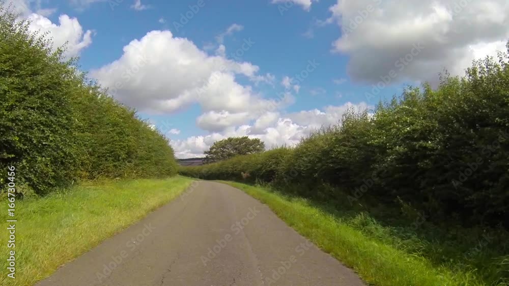 Driving along an empty narrow country road lined with tall hedges in Leicestershire, England. Vehicle POV. Driving along an empty narrow country road lined with tall hedges in Leicestershire, England. Vehicle POV.