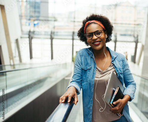 Confident young African entrepreneur riding an escalator in an o photo