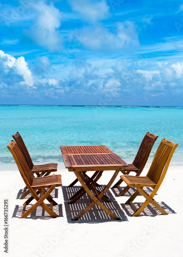 Wooden tables and chairs of tropical restaurant on the sand