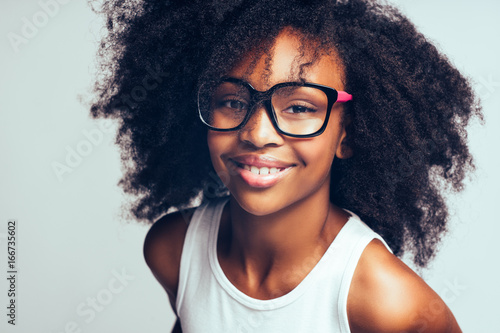 Cute little African girl wearing glasses against a gray backgrou