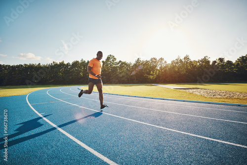 Fototapeta Naklejka Na Ścianę i Meble -  Fit young runner sprinting alone down a track