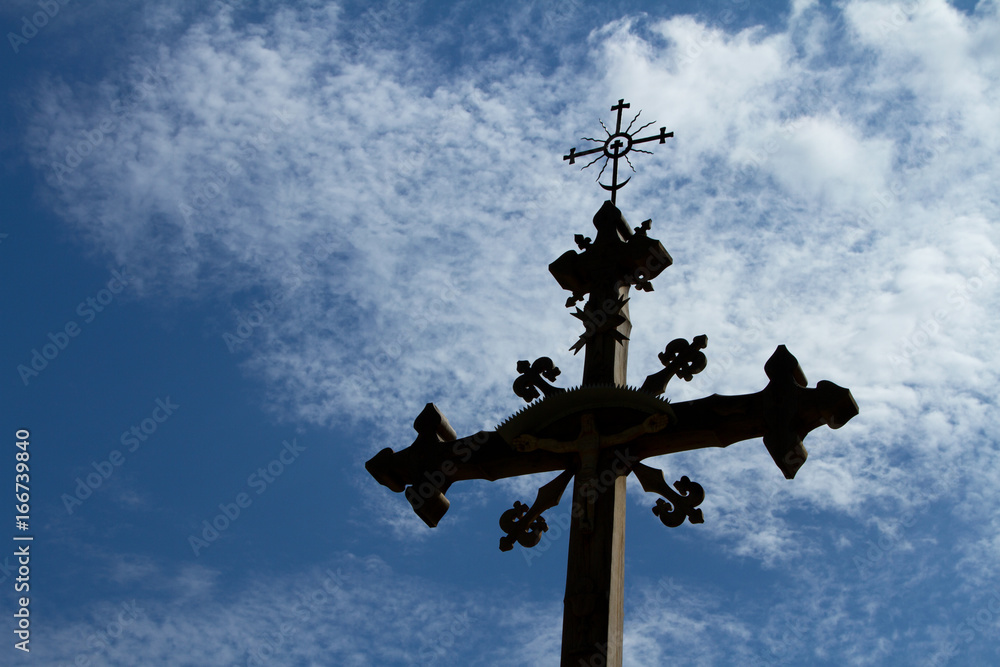 Old, historic wooden cross against the sky with white clouds Old, historic wooden cross against the sky with white clouds