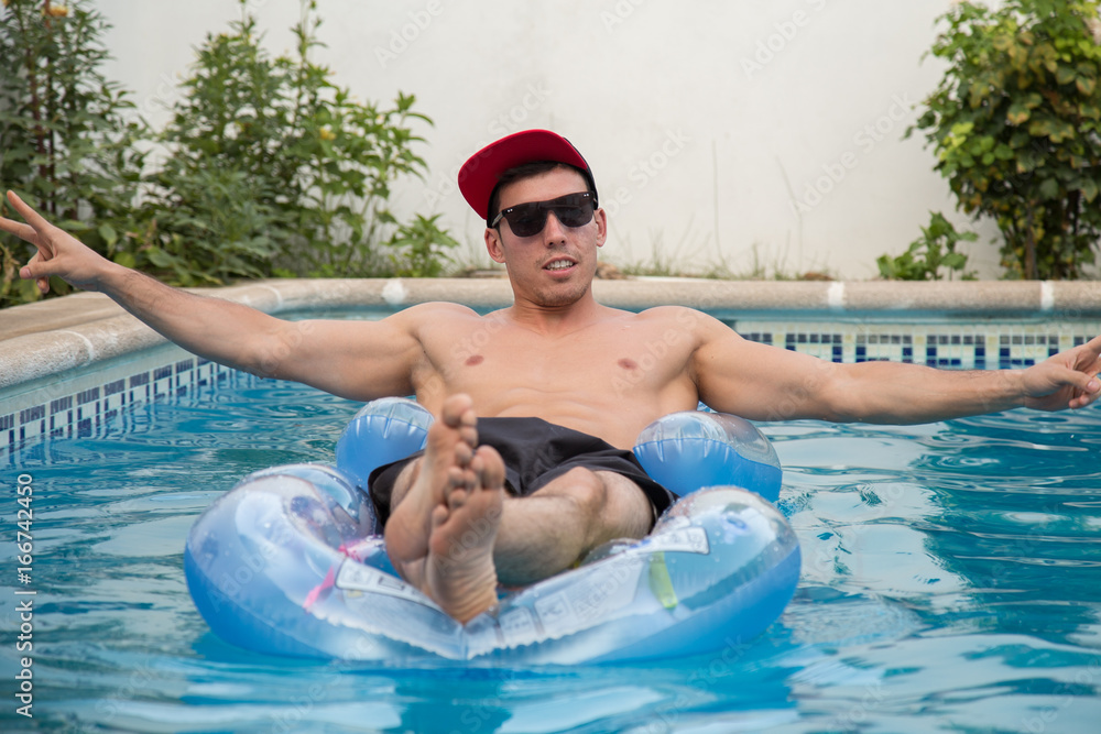 Young strong man on an air bed in the pool. 