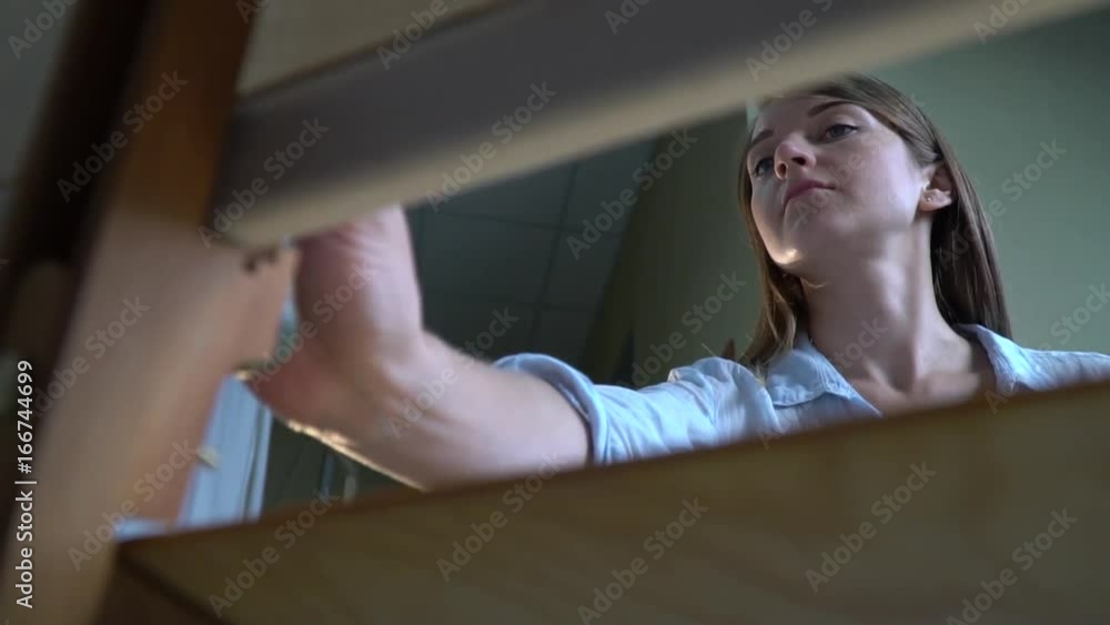 Brunette painter paints a picture on canvas view from behind an easel