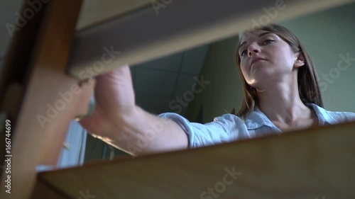 Brunette painter paints a picture on canvas view from behind an easel photo