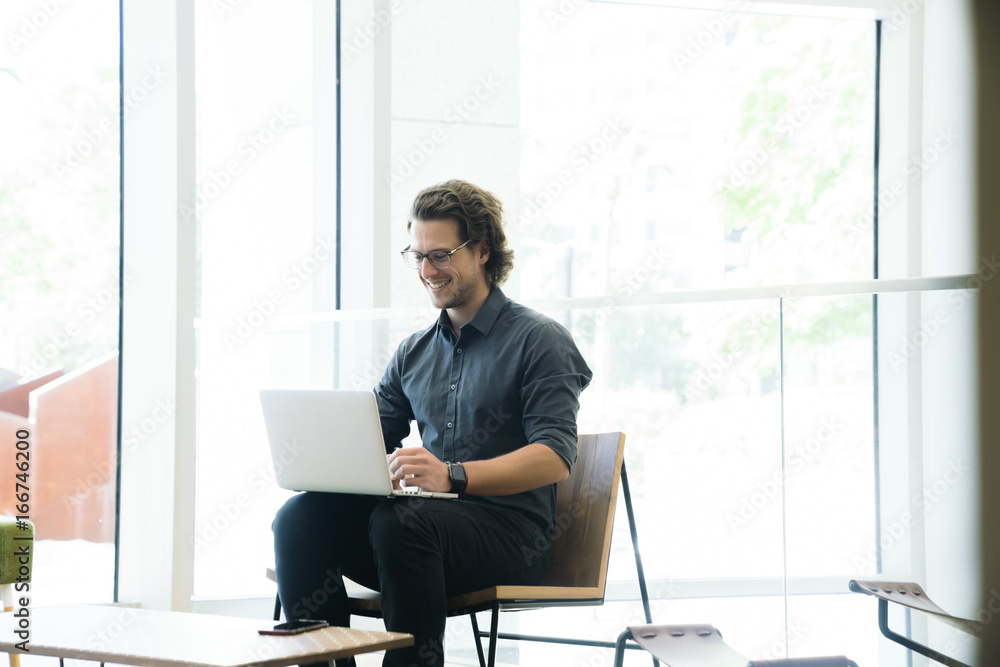 Hip man working on laptop in a modern tech business office Hip man working on laptop in a modern tech business office