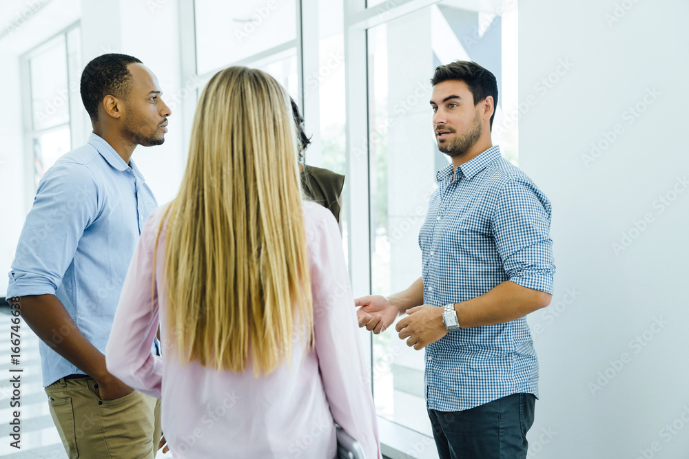 Coworkers meeting in hallway of modern office building Coworkers meeting in hallway of modern office building