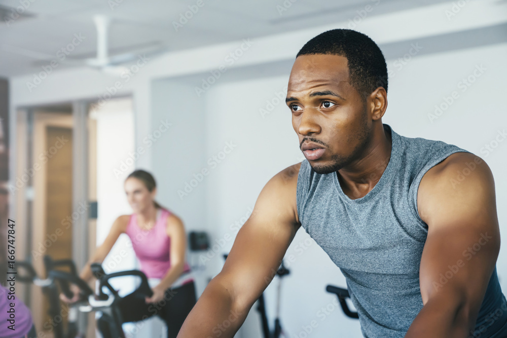 People cycling in a spin class at a gym People cycling in a spin class at a gym