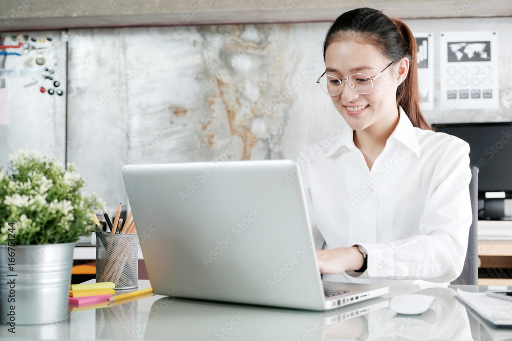 Young asian businesswoman working with laptop computer with smiling face, positive emotion, at office, office life concept Young asian businesswoman working with laptop computer with smiling face, positive emotion, at office, office life concept