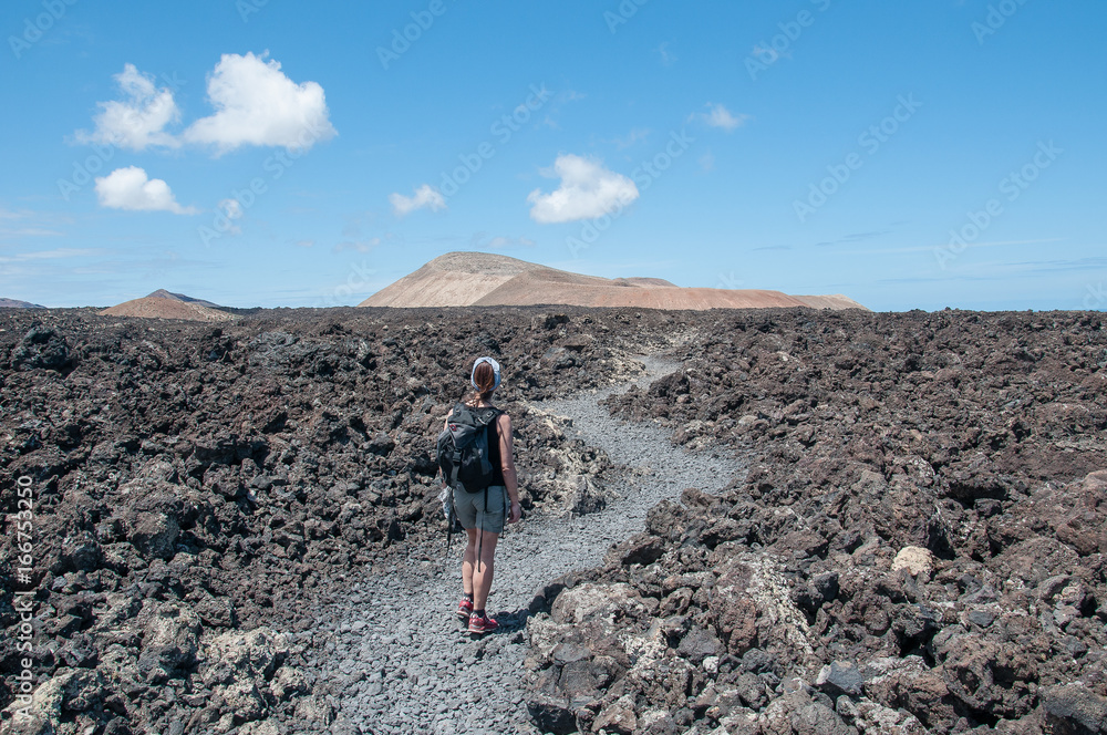 LANZAROTE, SPAIN - MAY 05 2017: girl walking along a path tracked in a volcanic landscape