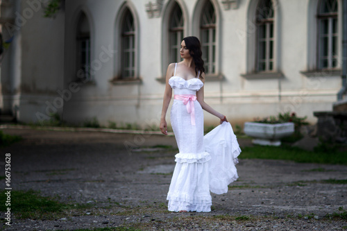 Glamorous young woman in a long white dress
