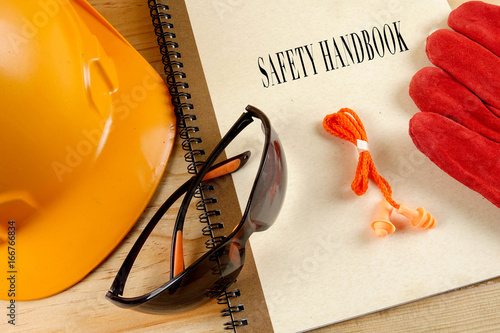 Safety hat,glove,glasses,ear plugs and note book with SAFETY HANDBOOK. Health and safety concept.