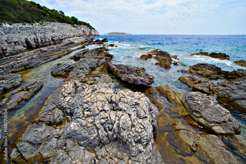 rocky coast in front of blue sea © Firma V