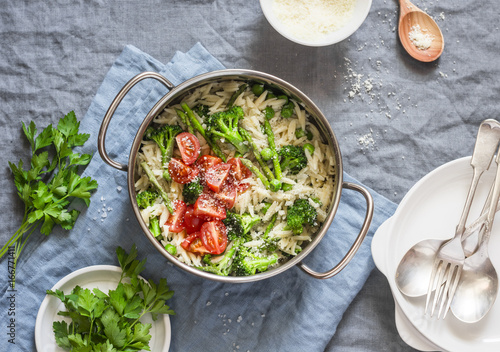 One pot orzo primavera. Orzo pasta with asparagus, broccoli, green peas and cream in a saucepan. On a light background, top view