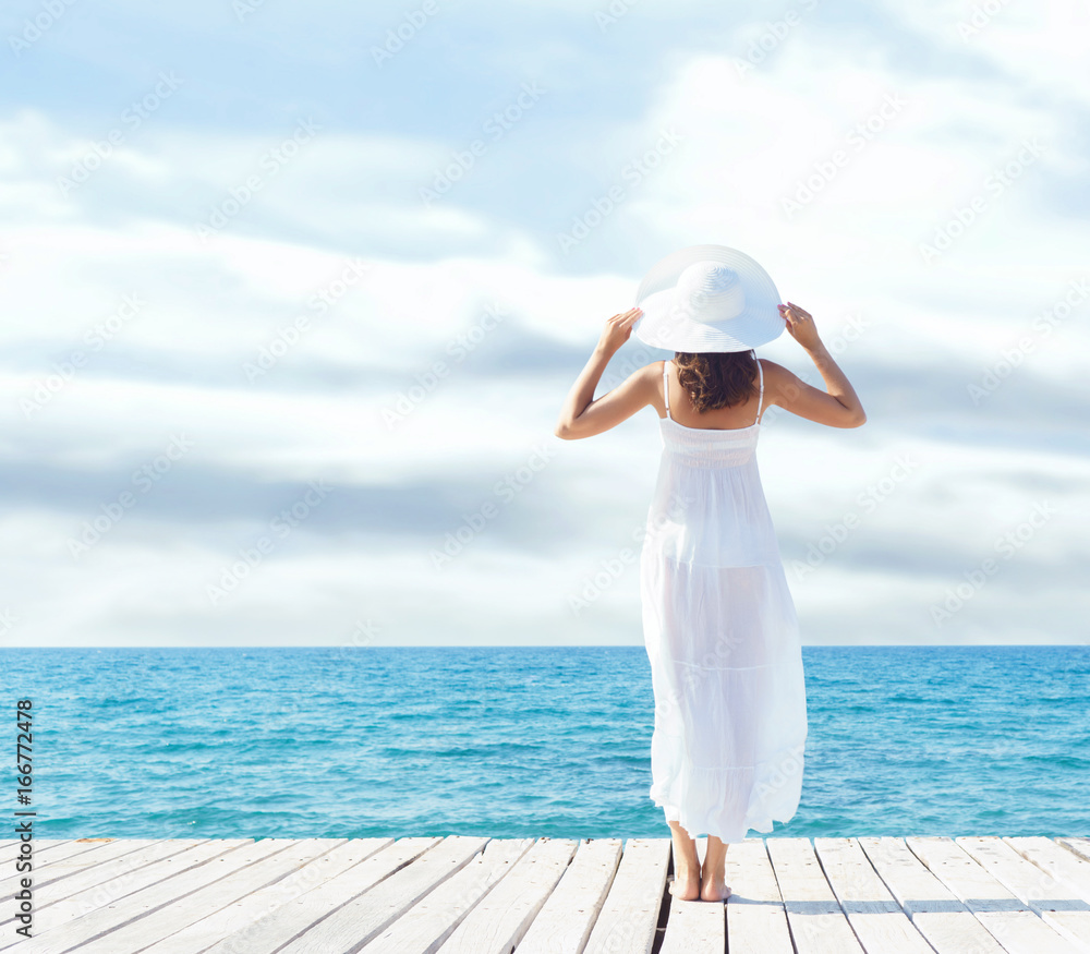 View from the back of beautiful and healthy girl on wooden pier. Vacation, resort and traveling concept.