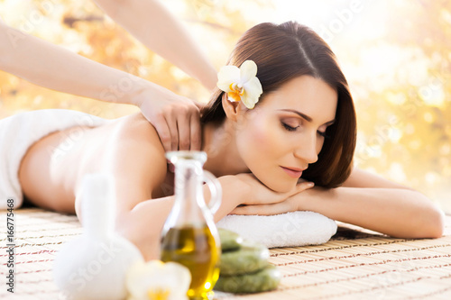 Beautiful, young and healthy woman in spa salon. Massage treatment over yellow autumn background. Traditional medicine and healing concept.