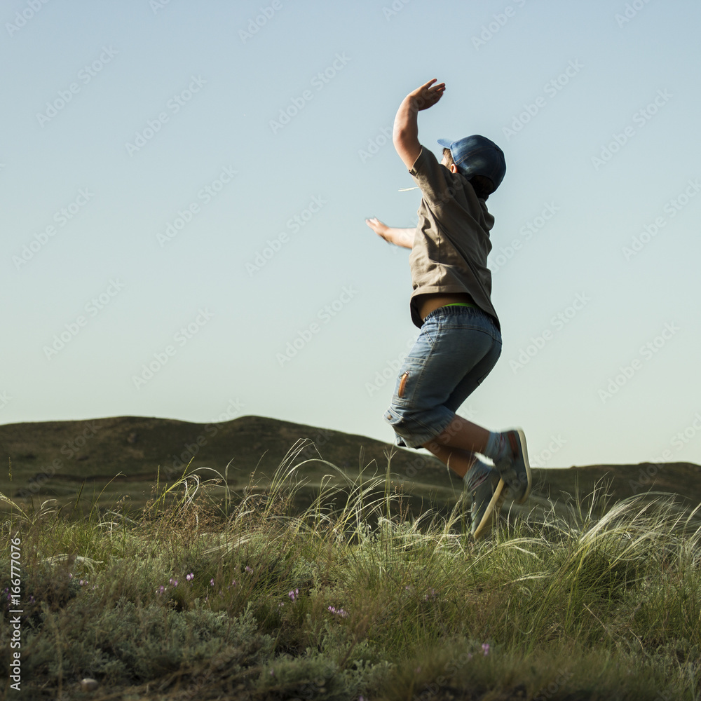Fototapeta premium Boy Jump in grass in background of the hills