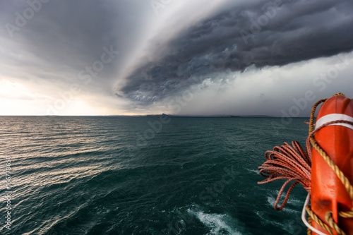 Foto Running from fast coming storm with boat, approaching storm on lake