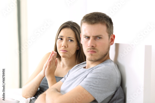 Wife begging and angry husband photo