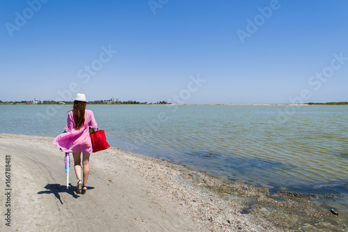 A woman walks along a deserted beach, leaving traces